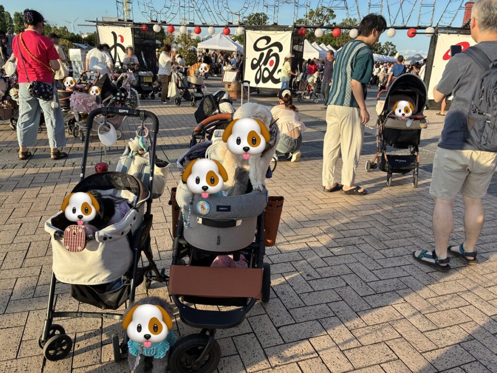 「犬夜市」の幟と提灯が並ぶ会場の通路。ペットカートに乗った犬たちと人でぎっしり混み合っている