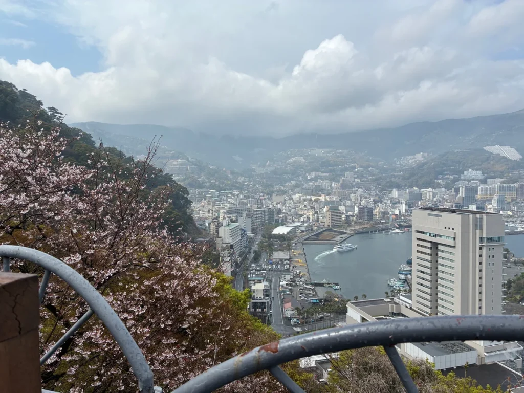 ロープウェイを降りたところから見下ろした熱海の街と海。手前に桜が咲いている